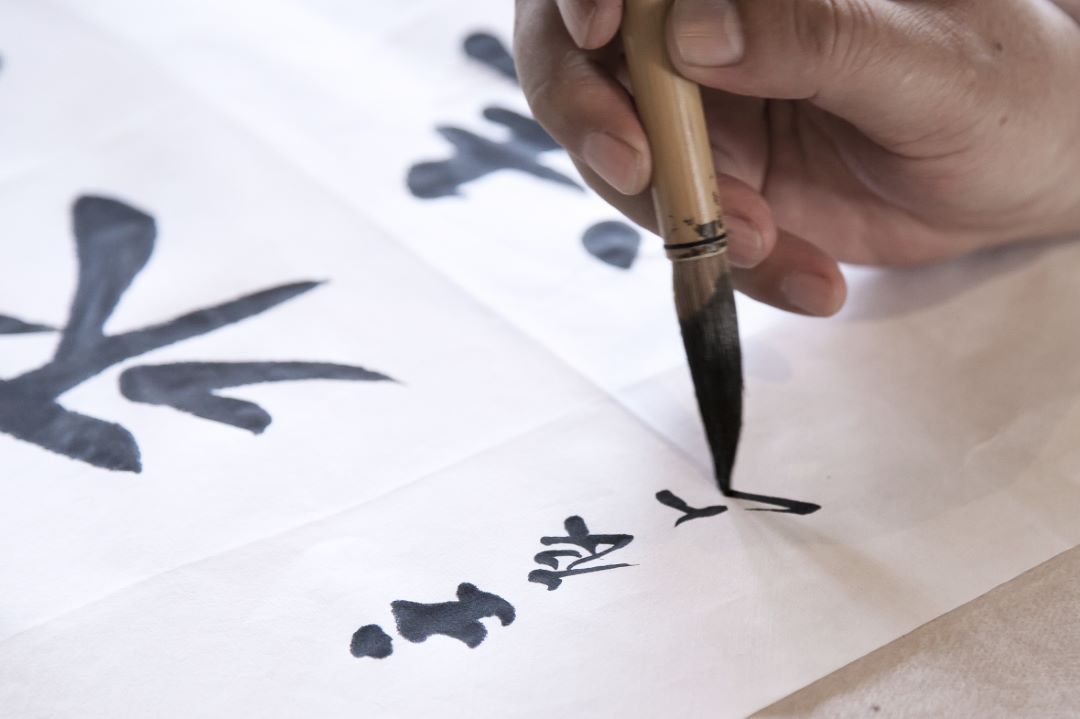 a person writes calligraphy with a traditional brush and ink